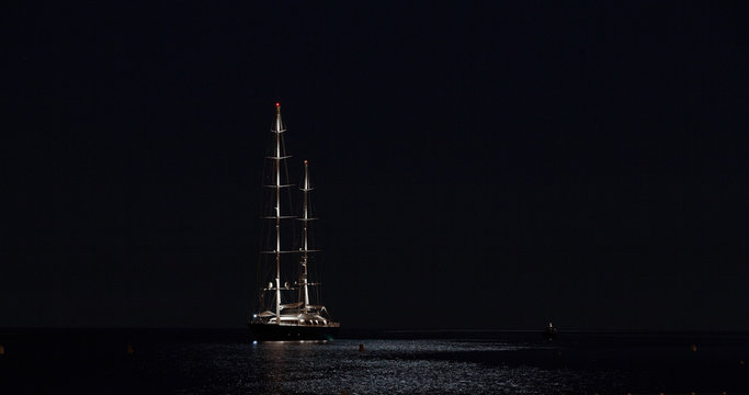 France, Menton, 28 august 2015: Large modern sailboat type Falcon standing on the lunar path at night , night lights and ship masts