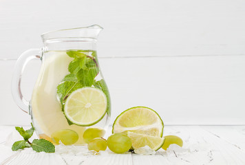 Refreshing homemade lime and mint cocktail over old vintage wooden table. Detox fruit infused flavored water. Clean eating. Copy space background