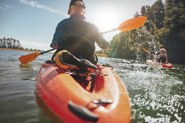 Man in kayak paddling on lake - obrazy, fototapety, plakaty