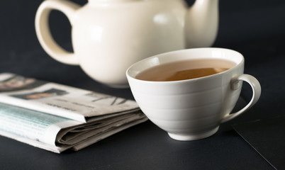 Cup of tea on the table with newspaper and notebook