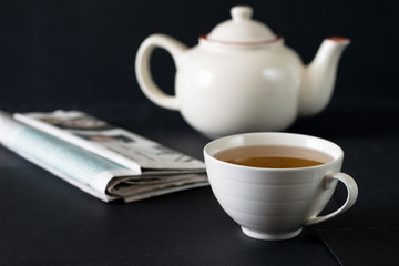 Cup of tea on the table with newspaper and notebook