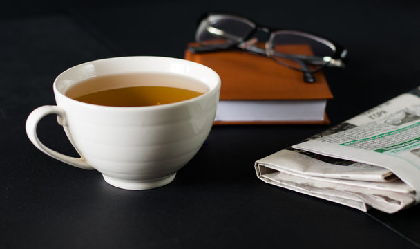 Cup of tea on the table with newspaper and notebook