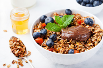 Healthy breakfast Fresh granola, muesli in bowl with milk, berries, chocolate hazelnut spread Copy space