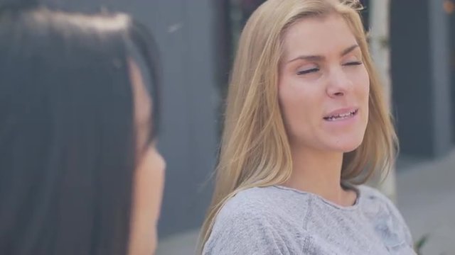 Close up of two friends sitting on a bench and talking