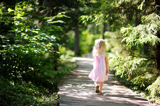 Little girl wearing pink dress taking a walk all alone