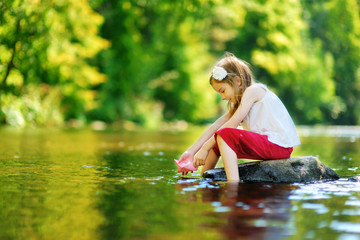 Fototapeta premium Cute little girl playing with paper boat