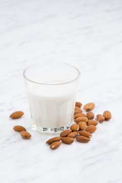 almond milk in a glass on white table, vertical