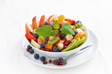 delicious fruit and berry salad in white bowl, top view