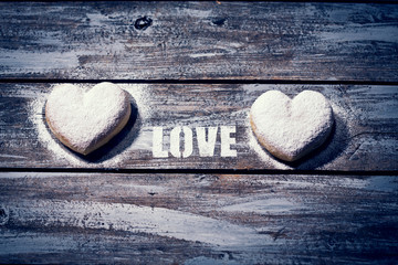 herzförmige Krapfen auf Holztisch mit Schriftzug Love