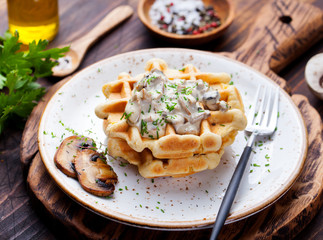 Savory waffles with corn and mushroom creamy sauce on a wooden background