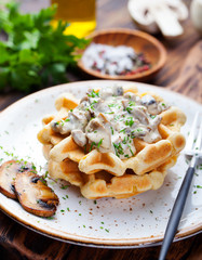 Savory waffles with corn and mushroom creamy sauce on a wooden background