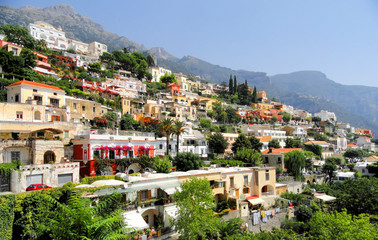 Fototapeta na wymiar Positano LivingRed car driving through the colourful living area in the hills of Positano