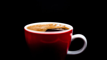 Red cup of coffee with coffee beans and dark background