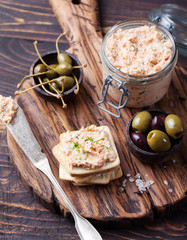 Smoked salmon and soft cheese spread, mousse, pate in a jar with crackers and capers on a wooden background