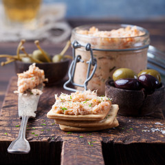Smoked salmon and soft cheese spread, mousse, pate in a jar with crackers and capers on a wooden...