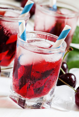 Cold cherry juice with ice on a white wooden background, selecti