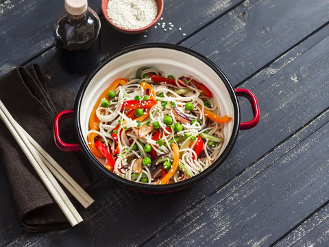 Healthy vegetarian food - vegetable stir fry and rice noodles in a bowl on dark wooden background.