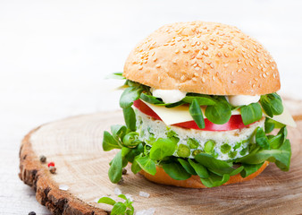 Vegetarian burger with egg and pea patty, fresh salad on a cutting wooden board