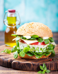 Vegetarian burger with egg and pea patty, fresh salad on a cutting wooden board