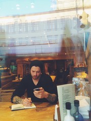 Handsome man in cafe works with notebook and phone