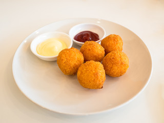 Deep fried cheese balls with sauce on white background