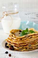 Milk and pancakes with honey and raisins, selective focus