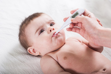 Doctor measures the temperature of little baby.