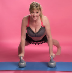 Woman leaning forward using kettle bells to exercise