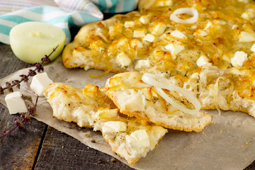 Focaccia with cheese and caramelized onions on a wooden table