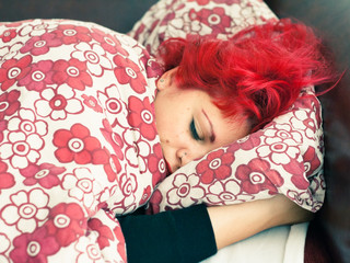 Young woman with red hair sleeping at the couch
