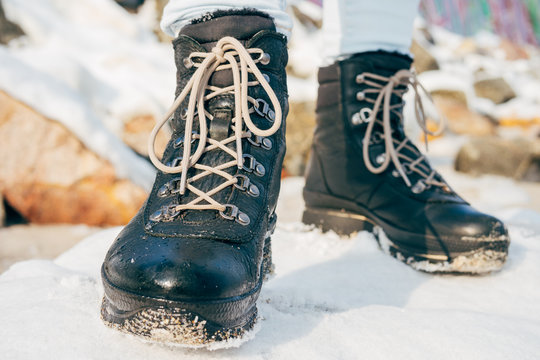 Female feet in winter boots with laces standing in the snow