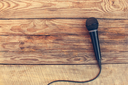 Microphone on wooden background. Toned image. 