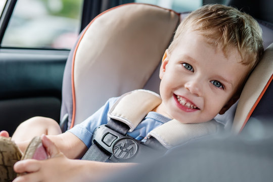 portrait happy toddler boy sitting in the car