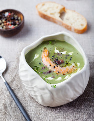 Broccoli, spinach cream soup with shrimp in a white bowls on a wooden board