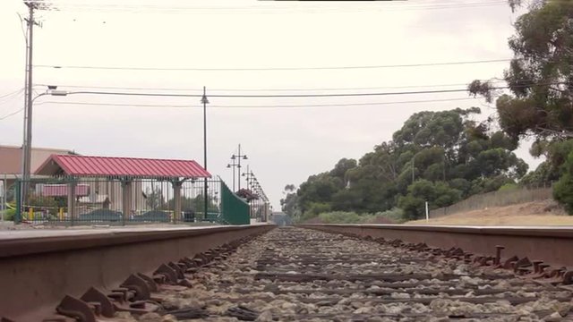 Slow camera dolly of train tracks near train station down the horizon with trees