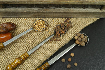 3 old metal spoons with spices on burlap background