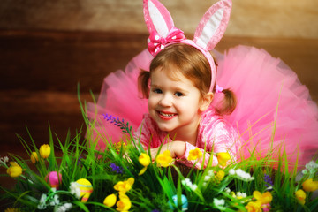 Happy child girl in  costume Easter bunny rabbit on grass and fl