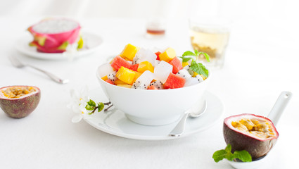Bowl of fresh exotic fruit salad on white summer background Healthy breakfast