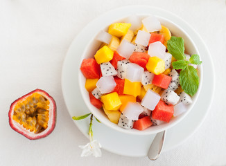 Bowl of fresh exotic fruit salad on white summer background Healthy breakfast