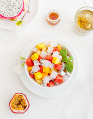 Bowl of fresh exotic fruit salad on white summer background Healthy breakfast Top view