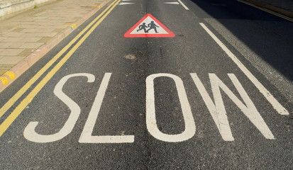 Word slow written on the street as warning sign