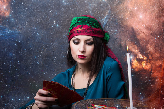 Young beautiful fortune teller wondering on the Tarot cards. Predicting the future, access to the astral