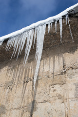 Large icicles hanging on the roof of the house in springtime