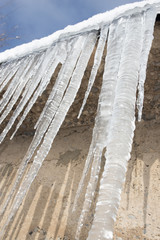 Fototapeta premium Large icicles hanging on the roof of the house in springtime