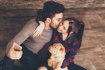 Happy couple with Shar Pei puppy taking selfie