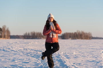 woman sitting in a yoga position on frozen lake snow