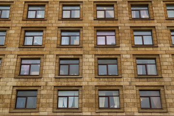 Many windows in row on facade of urban apartment building front view