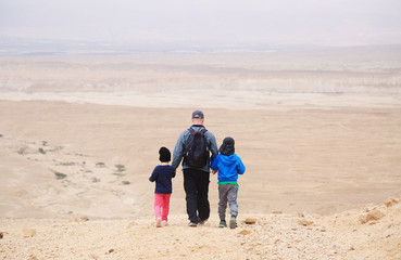 father hiking with two kids in the desert