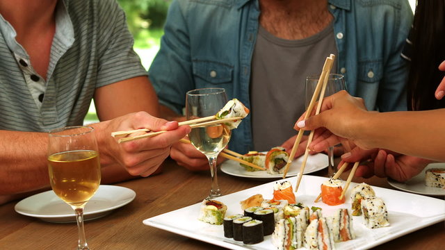 Happy friends eating sushi