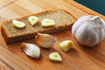Pieces of black bread and garlic on cutting board